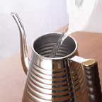 Silver teapot with a wooden handle being filled with water from a clear container.