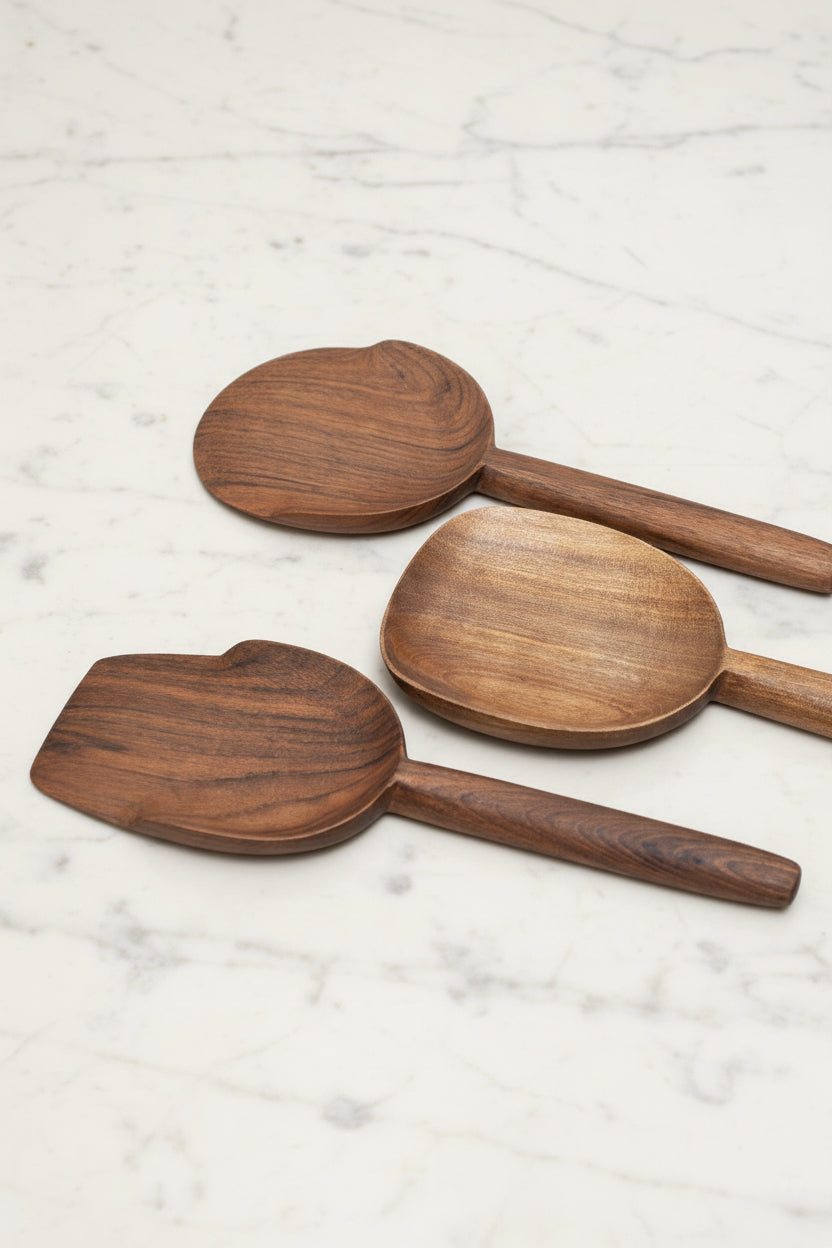Selection of 3 assorted Une Vie Nomade walnut serving spoons on a white marble surface.