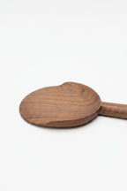 One Une Vie Nomade walnut serving spoon on a white surface.