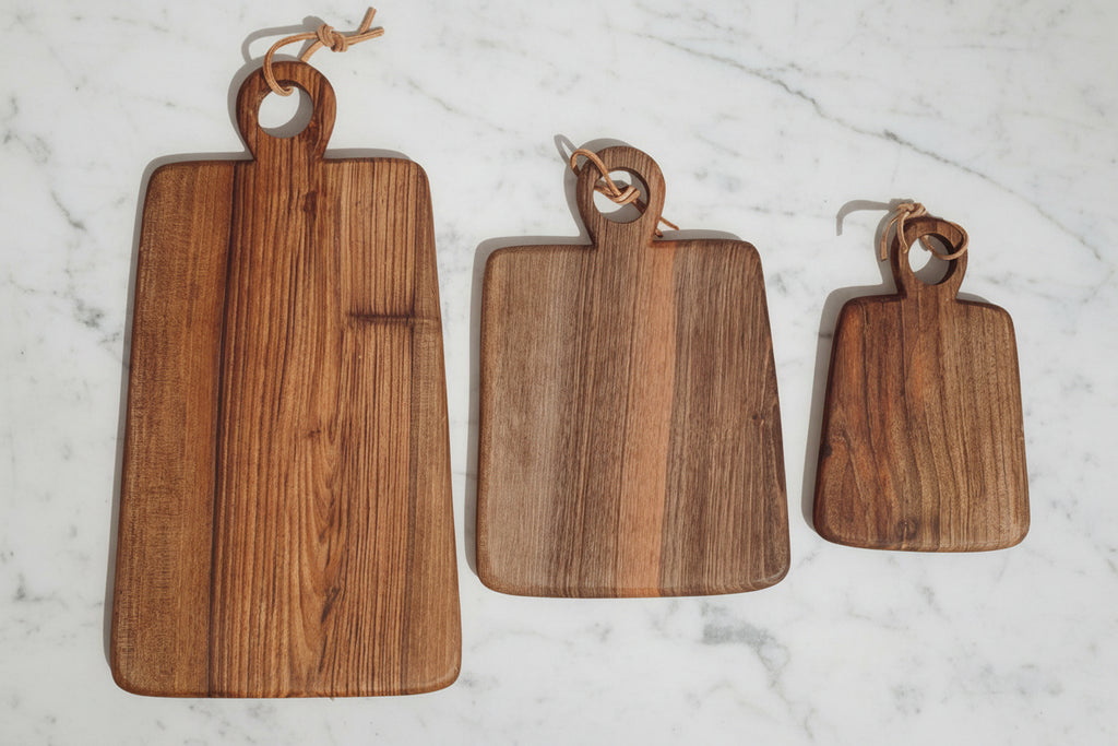 Three rectangular shaped Une Vie Nomade cutting boards on a white marble surface.