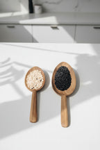 Two Une Vie Nomade walnut wood scoops on a white kitchen countertop. 