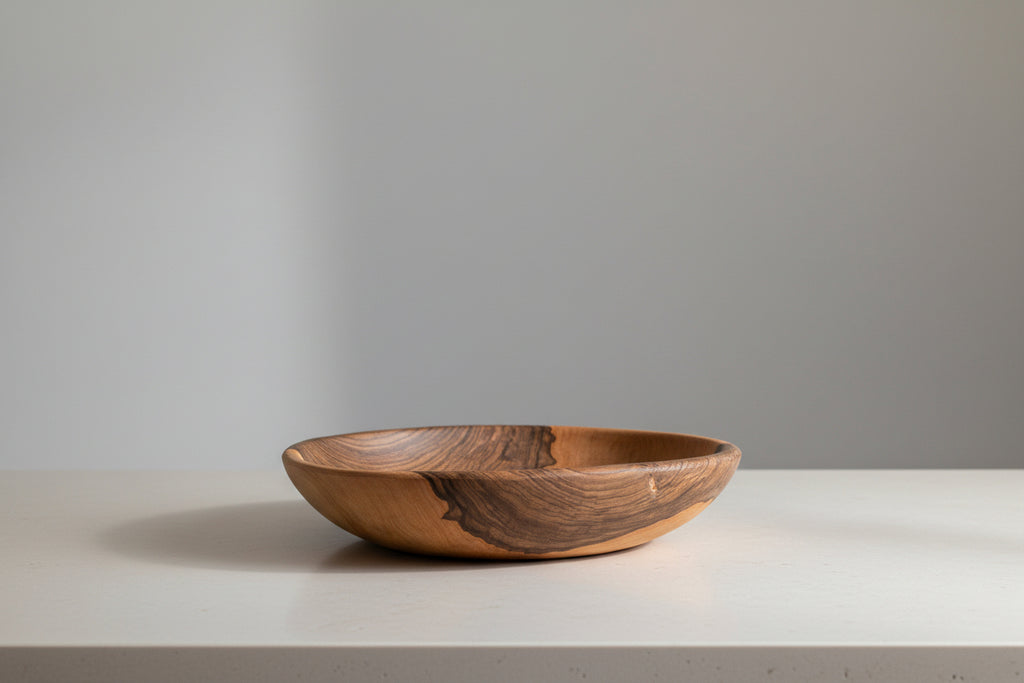 One large Une Vie Nomade walnut bowl shaped tray on a white countertop.