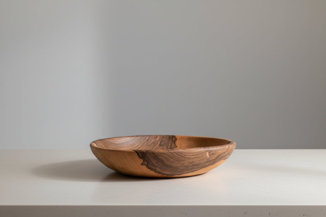 One large Une Vie Nomade walnut bowl shaped tray on a white countertop.