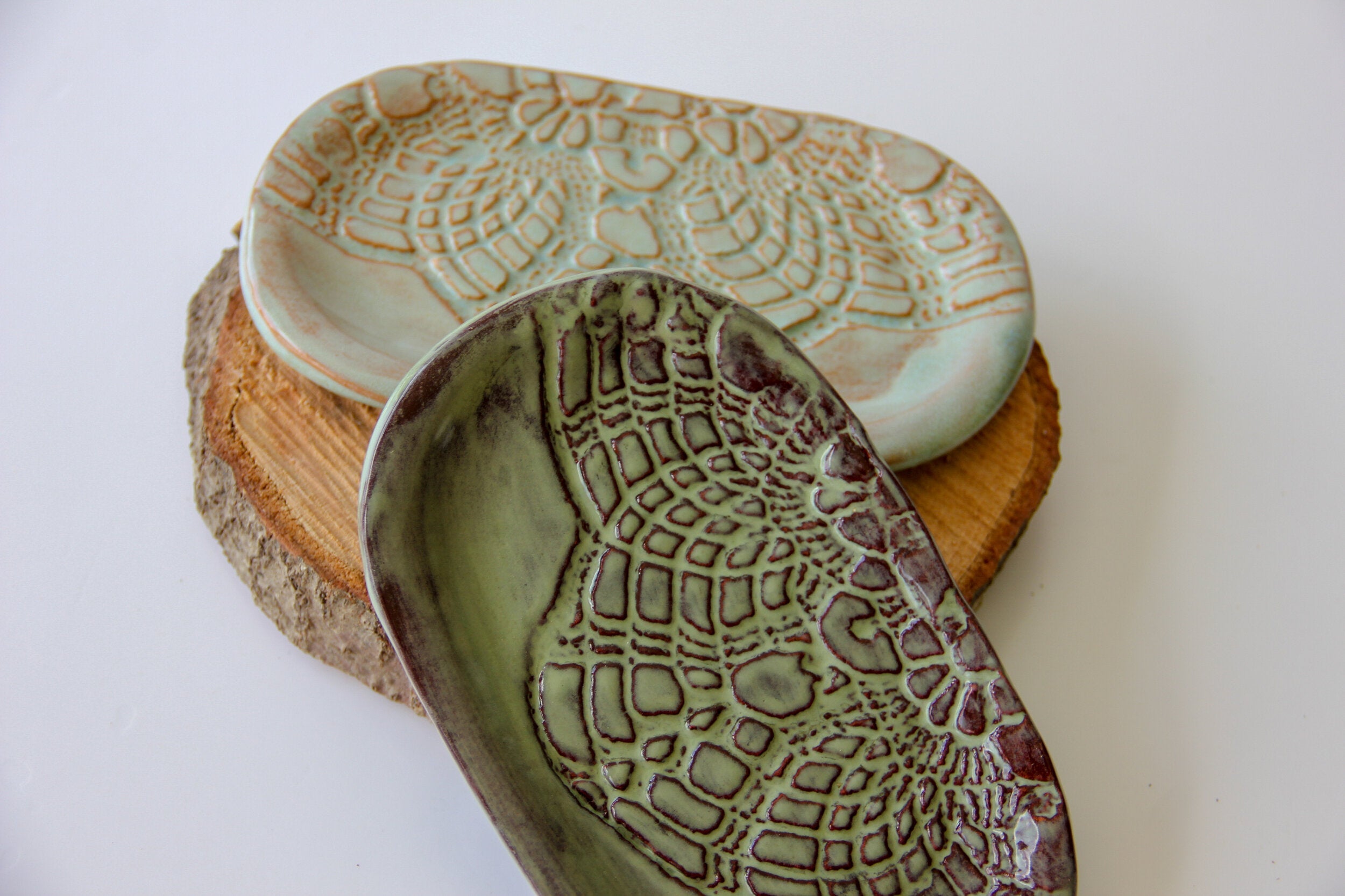 A light and a dark green oval shaped dish with a white background.
