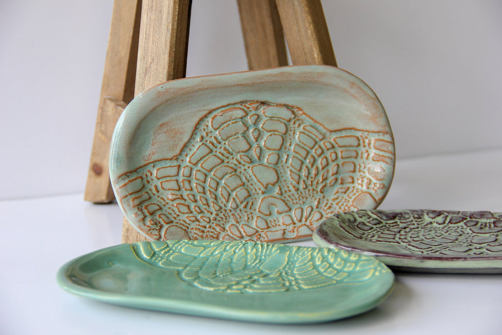 A light and a dark green, and a cream colored oval shaped dish with a white background.