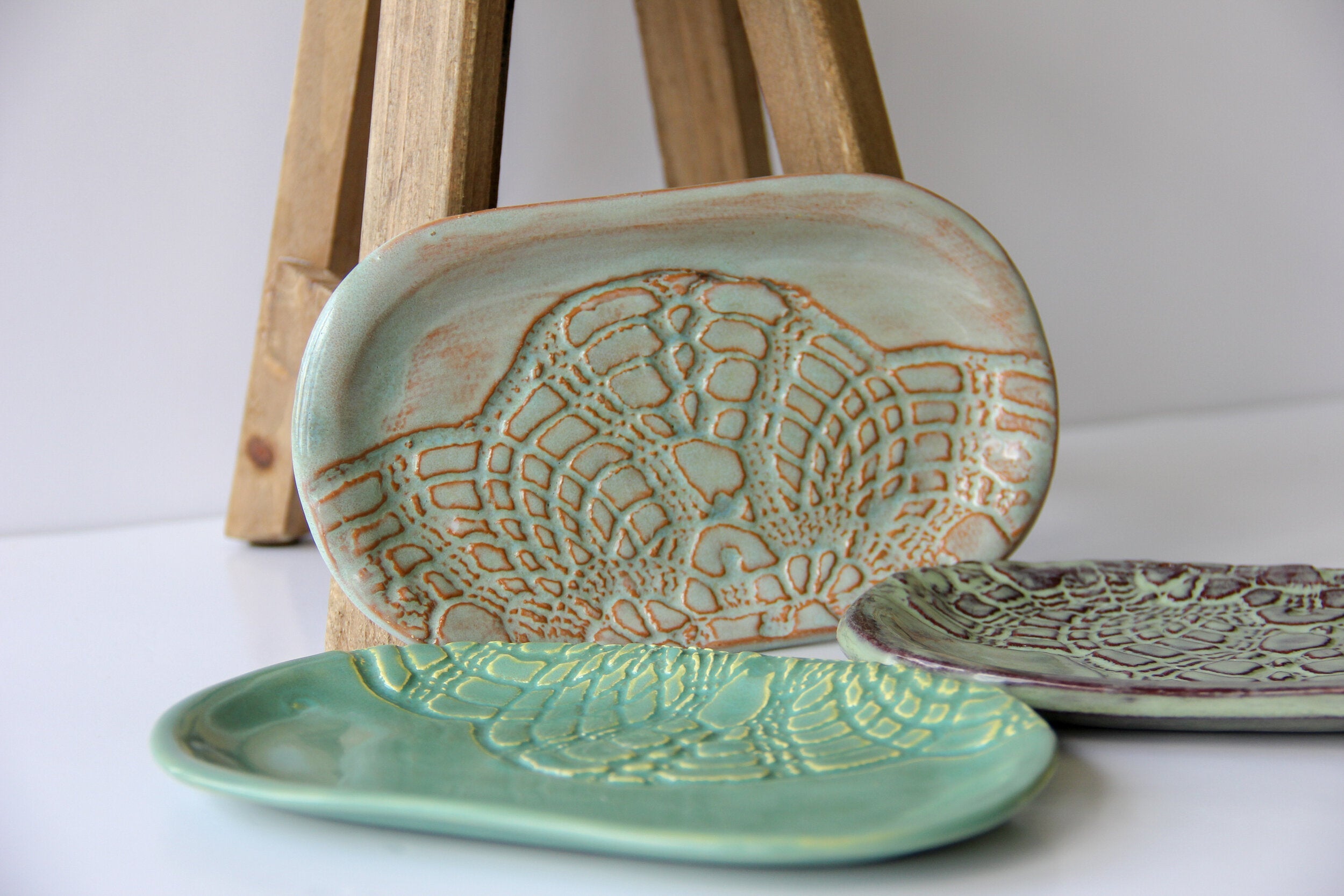 A light and a dark green, and a cream colored oval shaped dish with a white background.