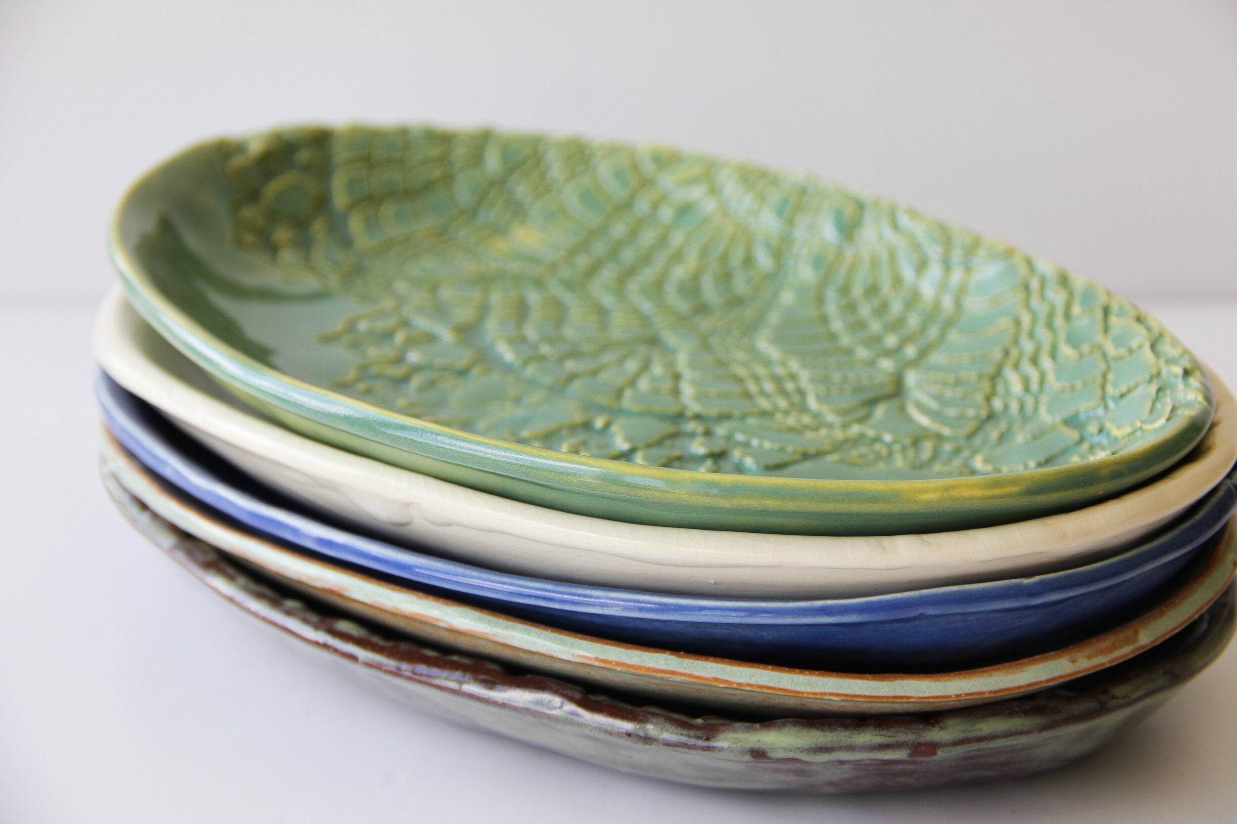 A stack of colored ceramic platters on a white surface.
