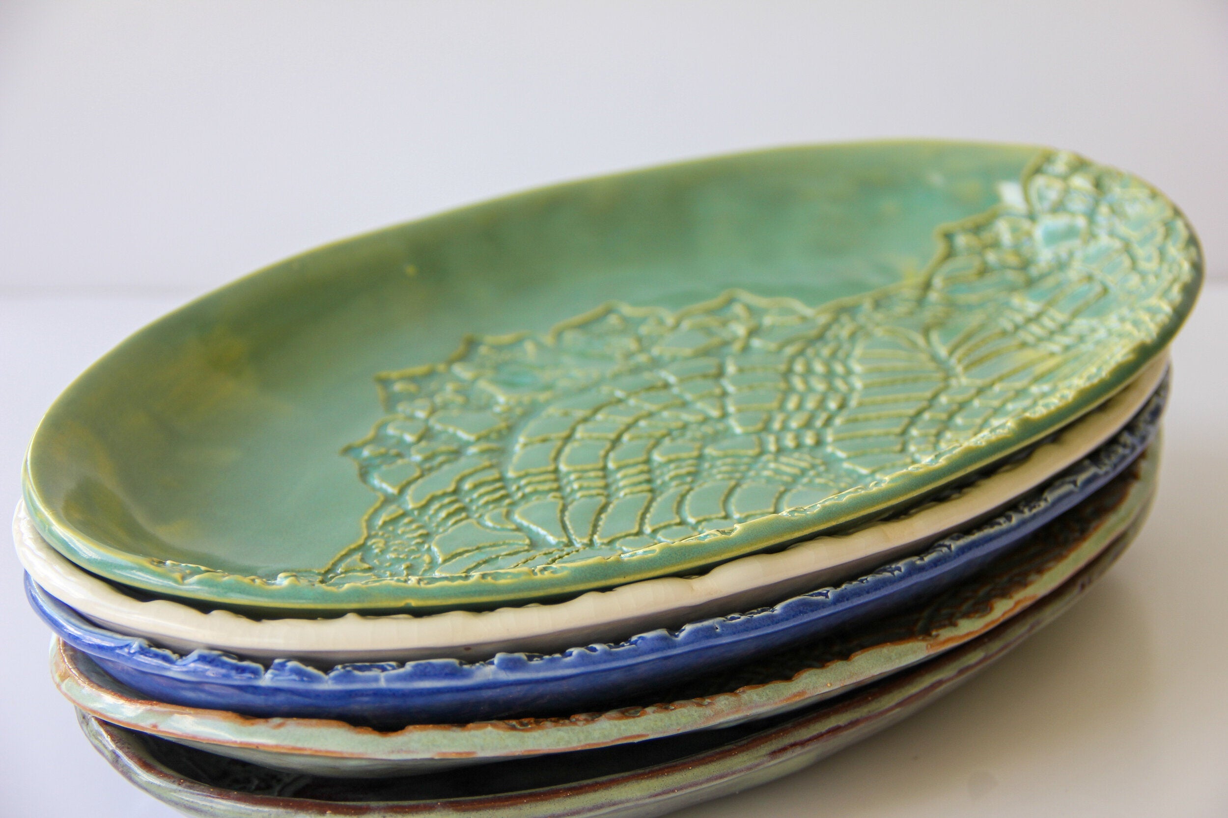 A stack of colored ceramic platters on a white surface.