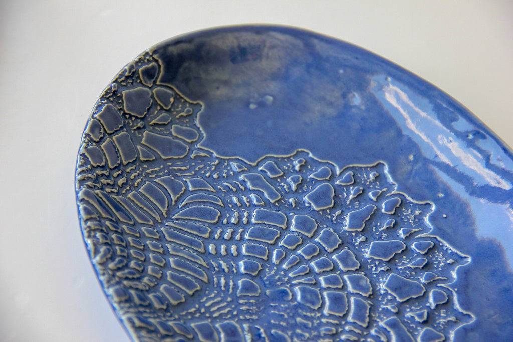 A blue oval platter on a white surface.