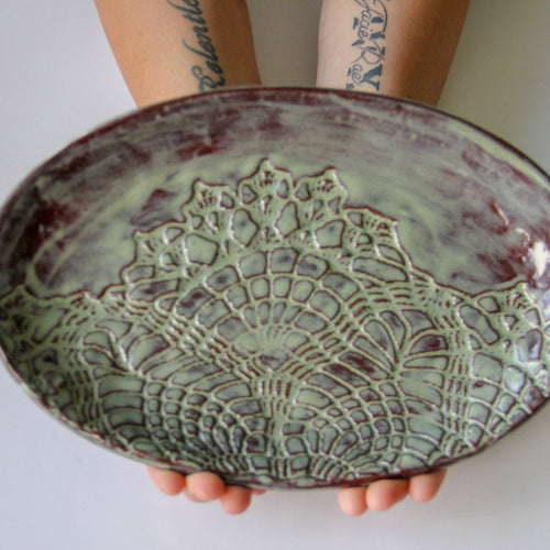 Green oval platter being held by a person.