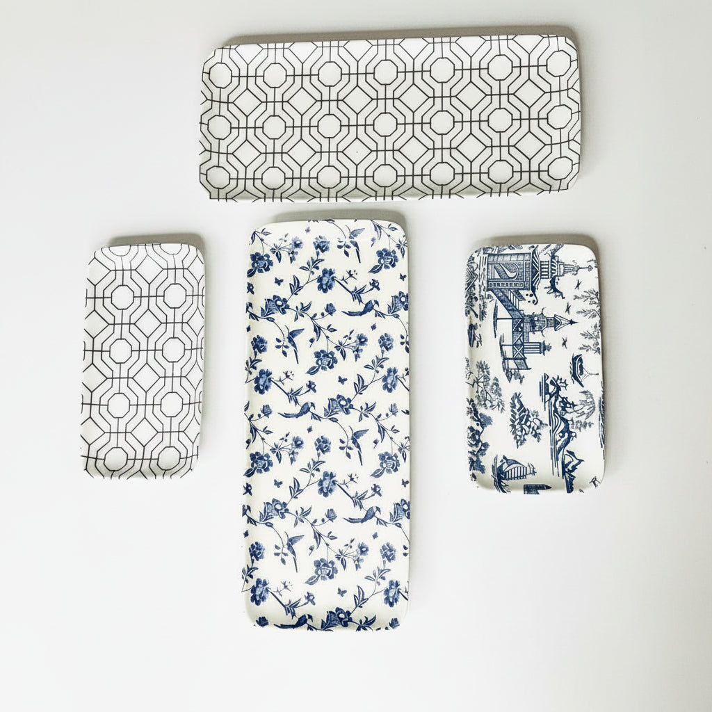 Set of four decorative mats with geometric, floral, and architectural patterns on white surface.