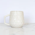 Cream colored honeycomb style coffee mug on a white background.