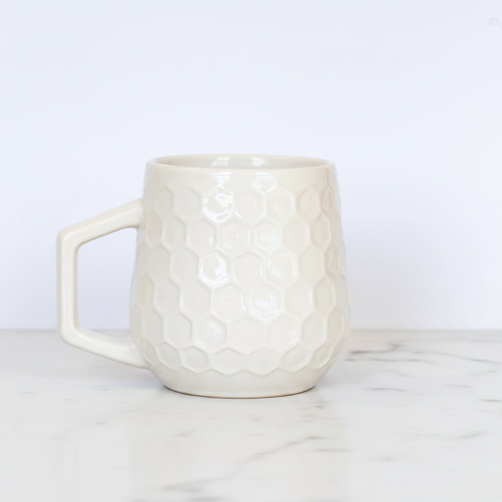 Cream colored honeycomb style coffee mug on a white background.