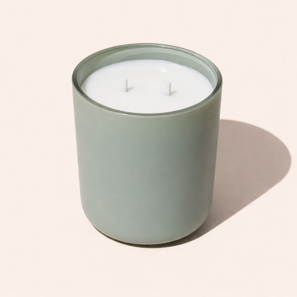 12 ounce scented two wick candle in a sage green glass container on a beige background