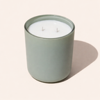 12 ounce scented two wick candle in a sage green glass container on a beige background