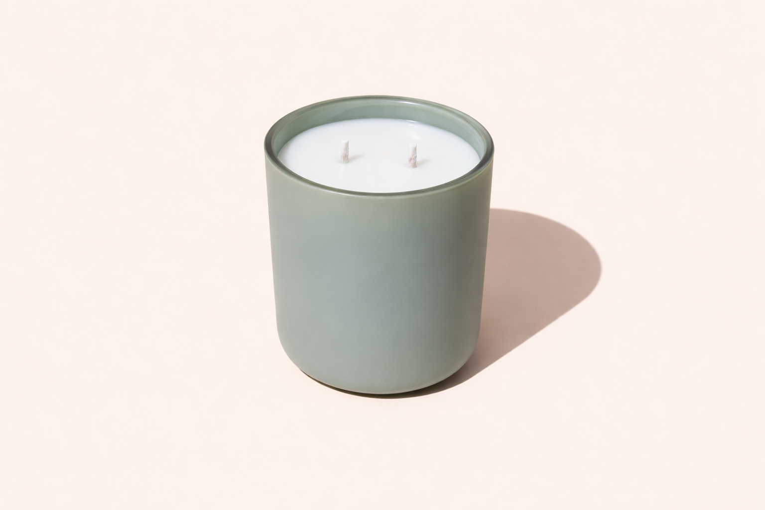 a two wick scented candle in a sage green container on a white background