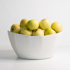 White porcelain bowl filled with apples a light background