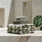Stack of green and white striped towels on a marble table with a neutral background
