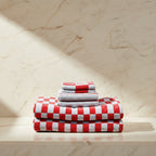 stack of folded towels with various red patterns on a light surface.