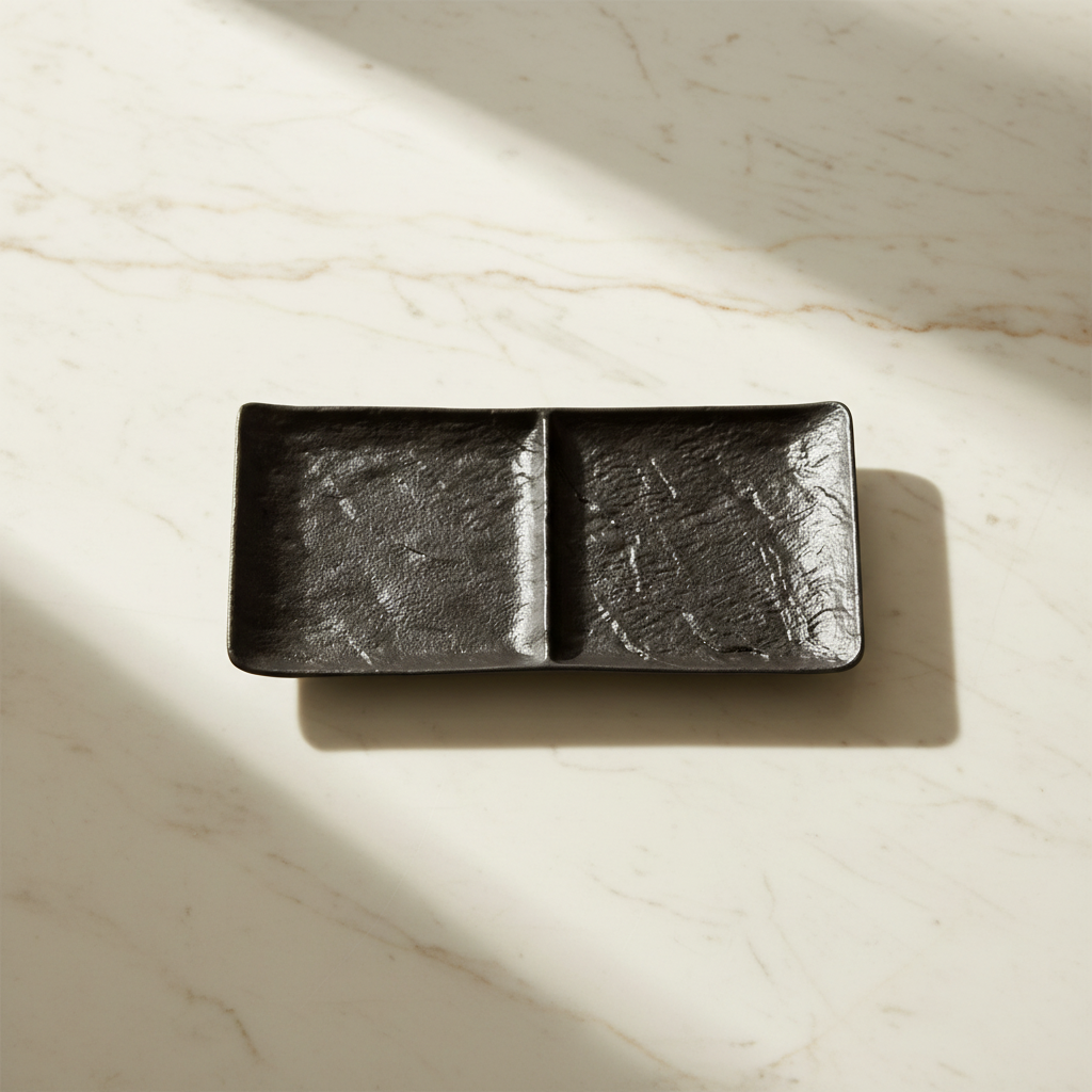Black two-section dish on creamy white marble