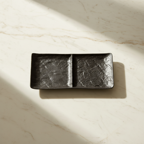 Black two-section dish on creamy white marble