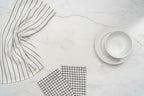 Three different white and black Organic Cotton Mart kitchen towels on a white counter.