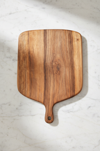 Large wide rectangular paddle-shaped Une Vie Nomade walnut cutting board on a white marble surface.