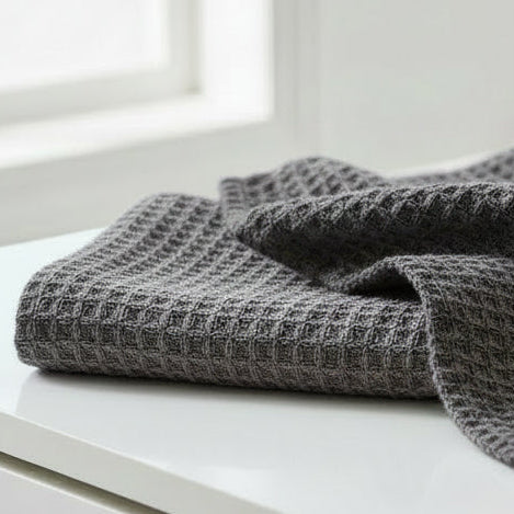 two gray waffle weave washcloths on a white surface.
