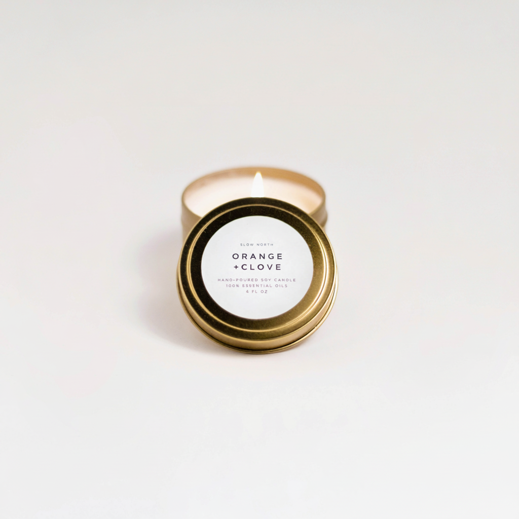 Orange + Clove Travel Tin on a white surface.