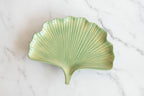 Green ginkgo plate on w white marble surface.