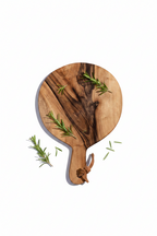 Small round Une Vie Nomade walnut cutting board on a white surface.