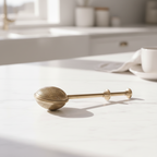 a gold tea infuser on a white marble surface
