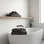 two stacks of folded charcoal gray waffle weave towels in a white bathroom.