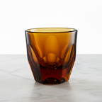 Vero Cappuccino Glass 6oz in amber — empty, handmade faceted glass on marble surface 