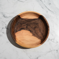 One large Une Vie Nomade walnut bowl shaped tray on a marble surface.